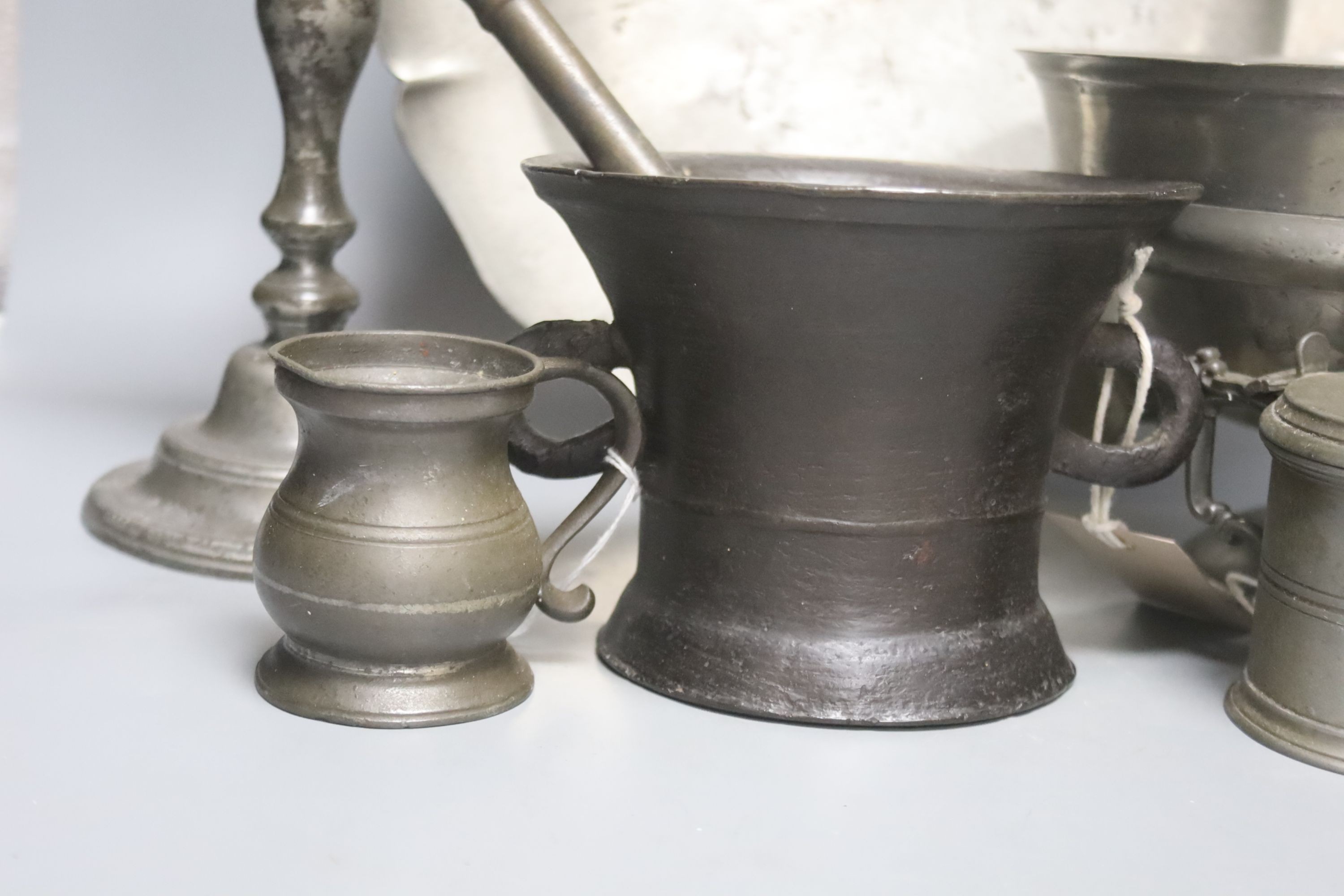 A pewter pedestal bowl, a barbed and crested dish, three other items of pewter and a 17th/18th century bronze pestle and mortar